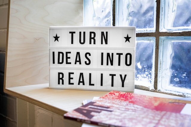 Image of a light board with 'Turn ideas into reality'. The board is in front of a window on a windowsill that is also holding artwork.
Photo by Mika Baumeister on Unsplash